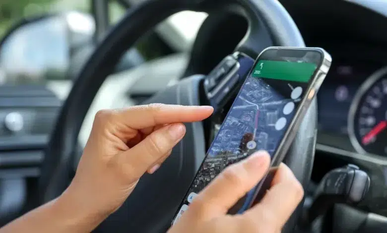 Female driver hand holding a phone with interface navigator on a screen