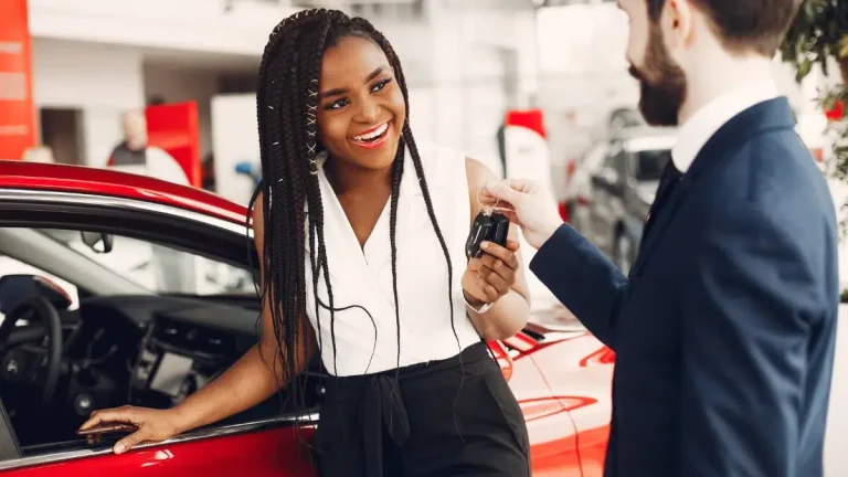 Stylish black woman in a car salon - Black woman getting keys at a car dealership