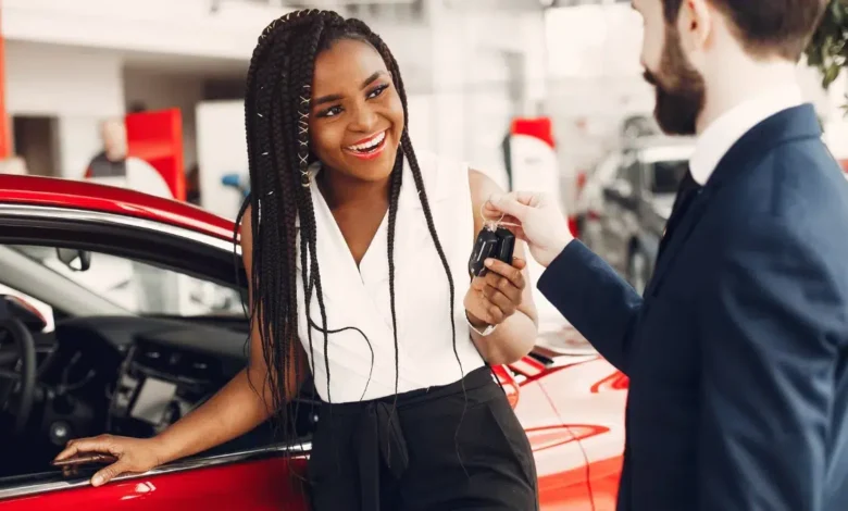 Stylish black woman in a car salon - Black woman getting keys at a car dealership