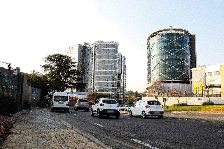 Best Cars for Uber and Bolt in South Africa (2026): Sedans That Qualify Cars and a minibus driving on a Johannesburg street lined with modern office towers