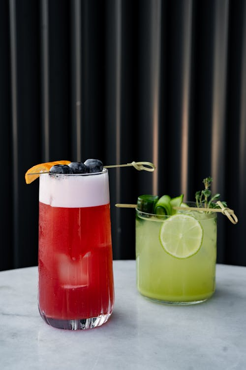Two cocktails with lime and blueberries on a table - Pexels Kadir Avşar