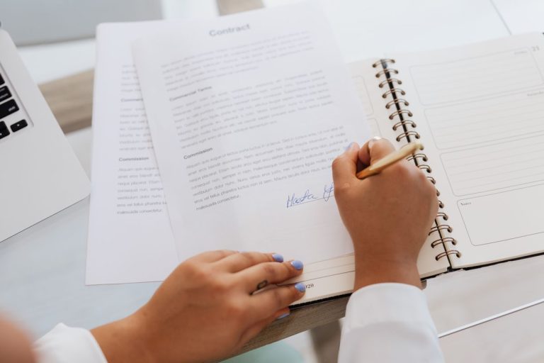 Hands signing papers on a desk